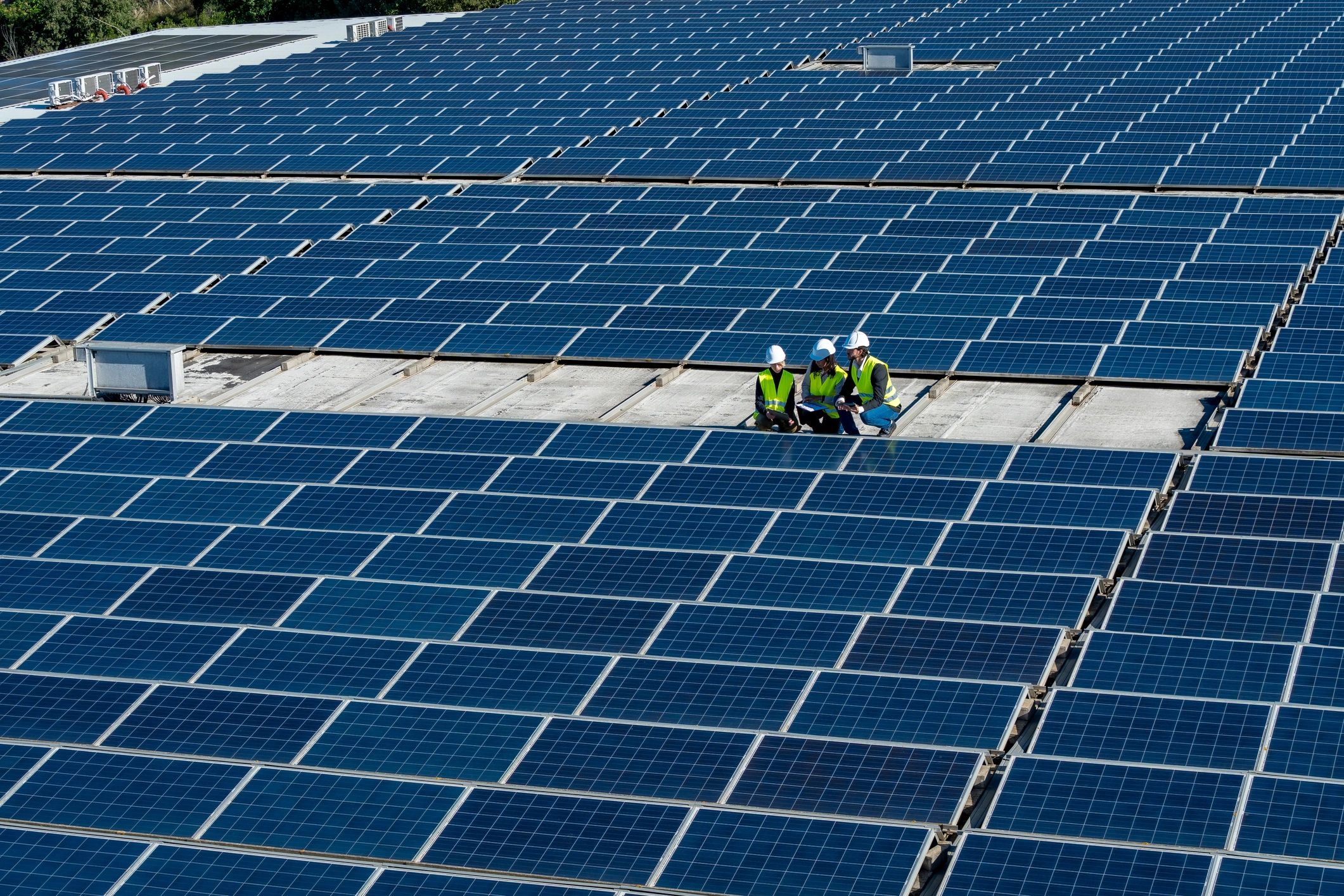 Engineers inspecting solar panels on huge rooftop installation